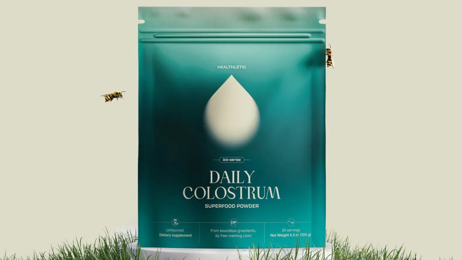 A green bag of Healthletic powder on a neutral background. The bag is in a patch of grass with two bees flying around it.