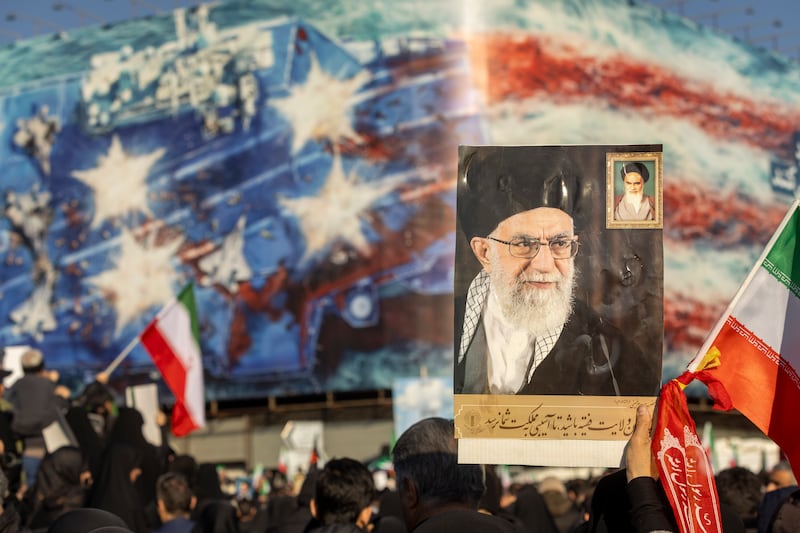 TEHRAN, IRAN - MARCH 1: A protest holds a poster of Ali Khamenei as thousands of people gather in Enghelab Square for a pro-government demonstration after Iranian state media confirmed the death of Ayatollah Ali Khamenei on March 1, 2026 in Tehran, Iran. Iran's Supreme Leader, Ayatollah Ali Khamenei, was confirmed killed after the United States and Israel launched a joint attack on Iran on February 28. Iran retaliated by firing waves of missiles and drones at Israel, and targeting U.S. allies in the region. (Photo by Majid Saeedi/Getty Images)