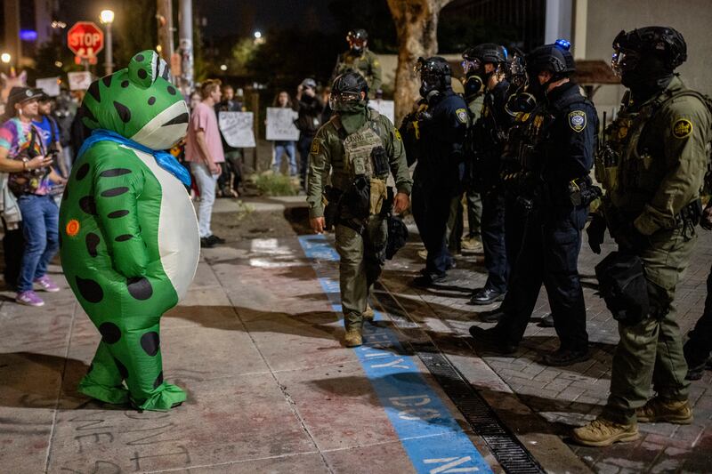 A protester in a frog costume stands in front of a line of federal law enforcement officers outside an Immigration and Customs Enforcement facility in Portland, Oregon on Oct. 6, 2025.