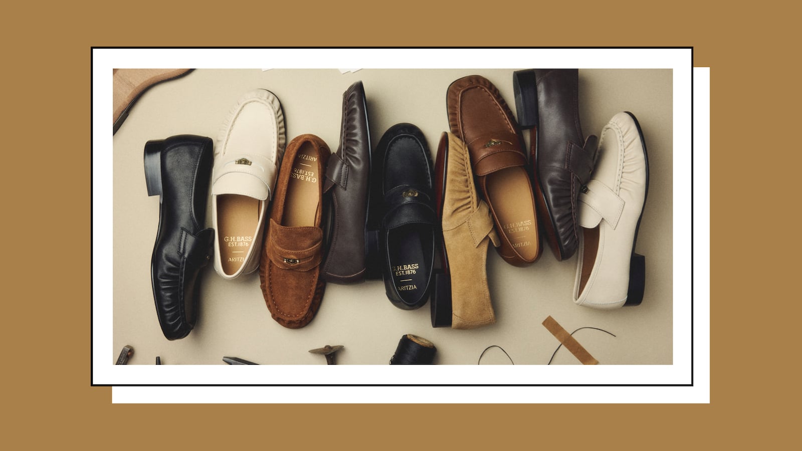 Eight G.H. Bass x Aritzia loafers arranged in a flat-lay on a beige surface, spanning styles and colorways including black, cream, tan suede, dark brown, camel, and white leather. Gold "G.H. Bass Est. 1876 / Aritzia" branding is visible on several insoles. Cobbler's props are scattered at the bottom of the frame.