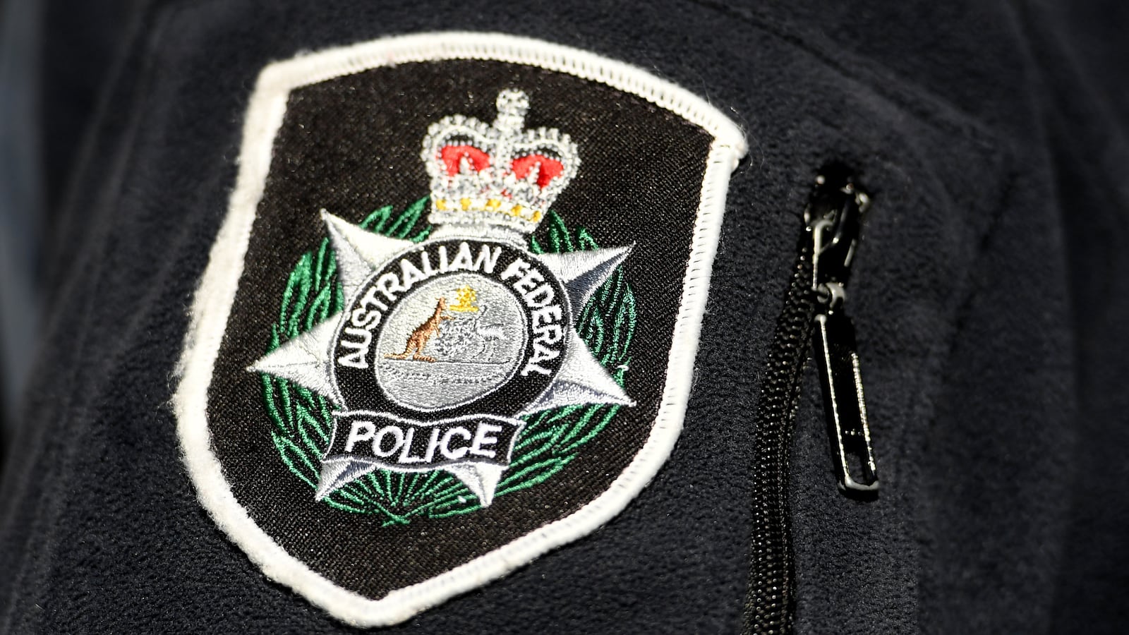 The AFP (Australian Federal Police) logo is seen on a uniform. A 45-year-old former childcare worker in Australia has been arrested and hit with 1,623 charges for allegedly sexually abusing nearly 100 young girls for over a decade.