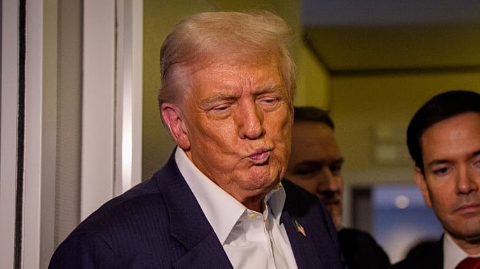 U.S. President Donald Trump, accompanied by U.S. Secretary of State Marco Rubio (R), takes a question from a reporter aboard Air Force One on October 27, 2025, in flight.