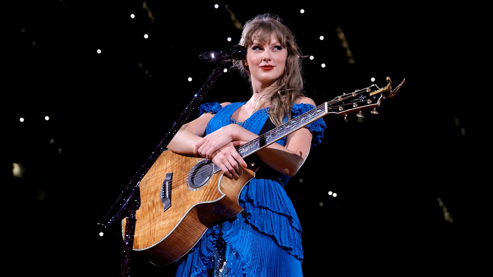 Taylor Swift holding a guitar during the Eras Tour “Surprise Songs” section.