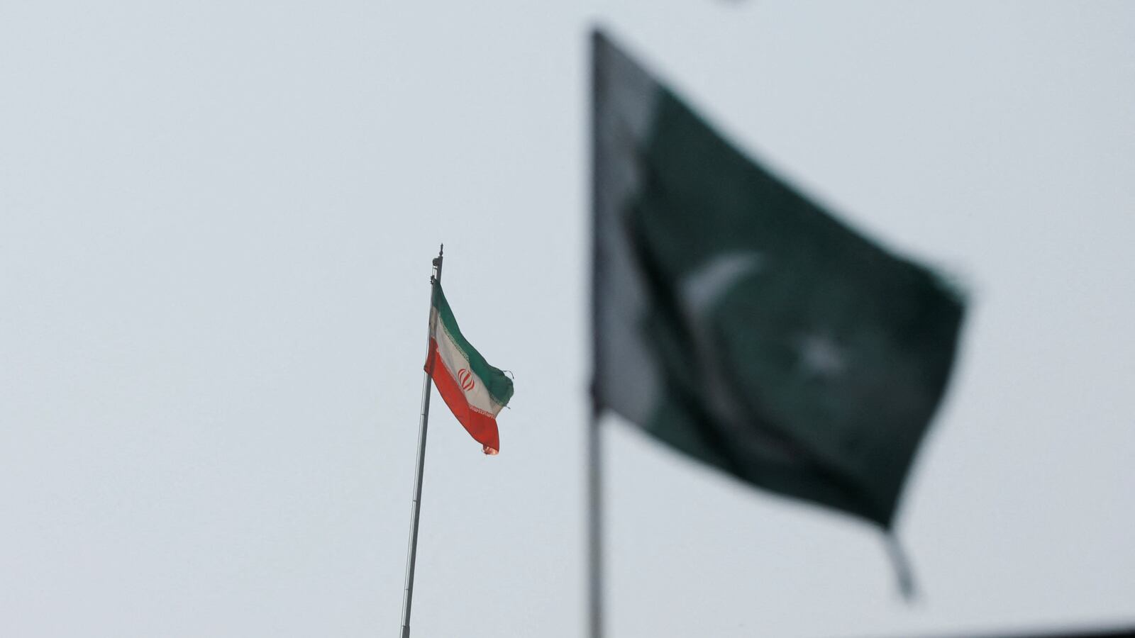 The flag of Iran is seen over its consulate building in Karachi, with Pakistan's flag in the foreground.