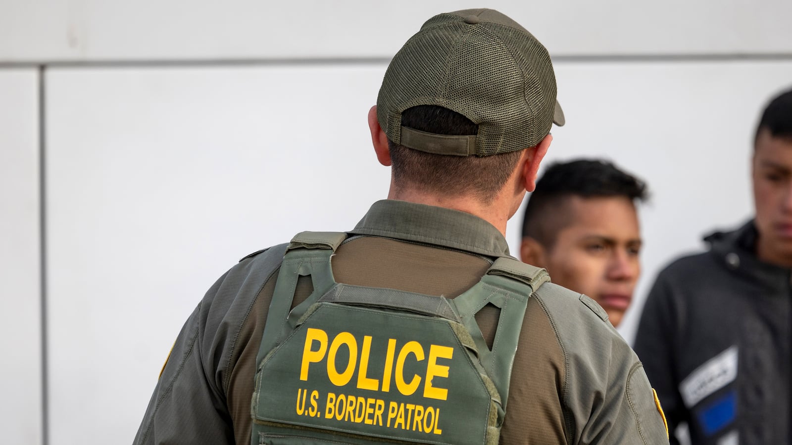 EAGLE PASS, TEXAS - JANUARY 07: A U.S. Border Patrol agent watches as immigrants prepare to board a bus after crossing the U.S.-Mexico border on January 07, 2024 in Eagle Pass, Texas.