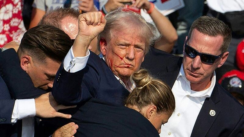 TOPSHOT - Republican candidate Donald Trump is seen with blood on his face surrounded by secret service agents as he is taken off the stage at a campaign event at Butler Farm Show Inc. in Butler, Pennsylvania, July 13, 2024. Donald Trump was hit in the ear in an apparent assassination attempt by a gunman at a campaign rally on Saturday, in a chaotic and shocking incident that will fuel fears of instability ahead of the 2024 US presidential election.
The 78-year-old former president was rushed off stage with blood smeared across his face after the shooting in Butler, Pennsylvania, while the gunman and a bystander were killed and two spectators critically injured. (Photo by Rebecca DROKE / AFP) (Photo by REBECCA DROKE/AFP via Getty Images)