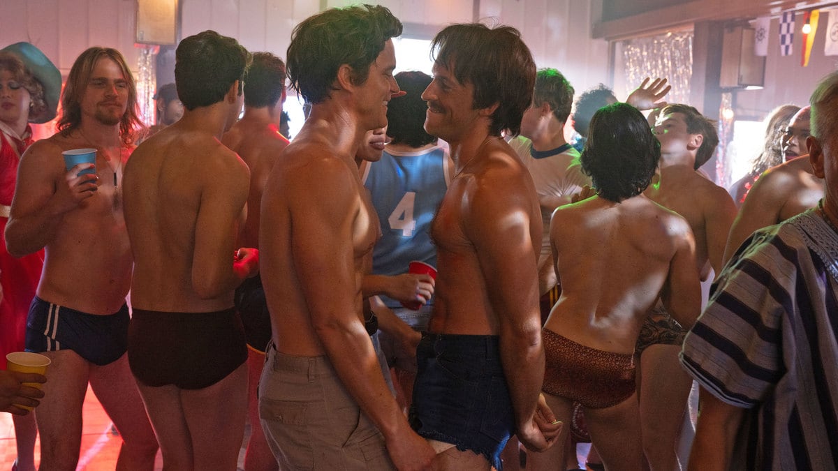 Matt Bomer and Jonathan Bailey dance shirtless surrounded by other shirtless men in a still from ‘Fellow Traveler’