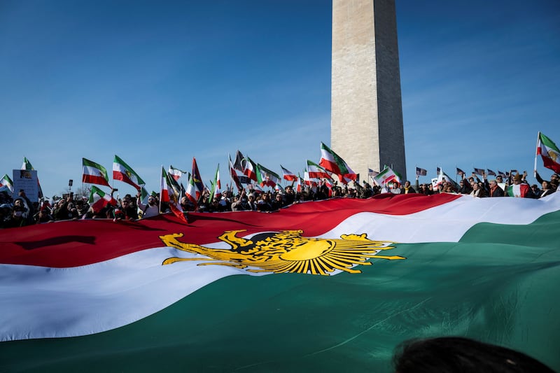 Demonstrators hold a large Iranian flag dating from before the 1979 Islamic revolution during a march in support of the people of Iran by members of the American-Iranian community in Washington, DC, on February 14, 2026. The demonstration comes after the bloody crackdown on protesters last month, while US President Donald Trump has been massing warships in the Middle East and declared Friday that a change of government in Iran would be the "best thing that could happen". (Photo by ROBERTO SCHMIDT / AFP via Getty Images)