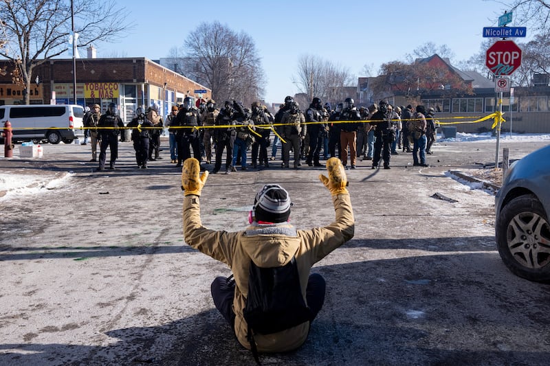 MINNEAPOLIS, MN. - JANUARY 2026: A protester sits on the street with his arms up in front of a gaggle of federal agents and Minneapolis Police on W. 27th St and Nicollet Avenue in south Minneapolis after Alex Pretti was fatally shot by federal agents in the area early Saturday morning, January 24, 2026. (Photo by Richard Tsong-Taatarii/The Minnesota Star Tribune)