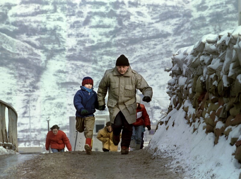 A father and son run to avoid snipers across a sandbagged bridge in the Olympic village area of Dobrinja January 4