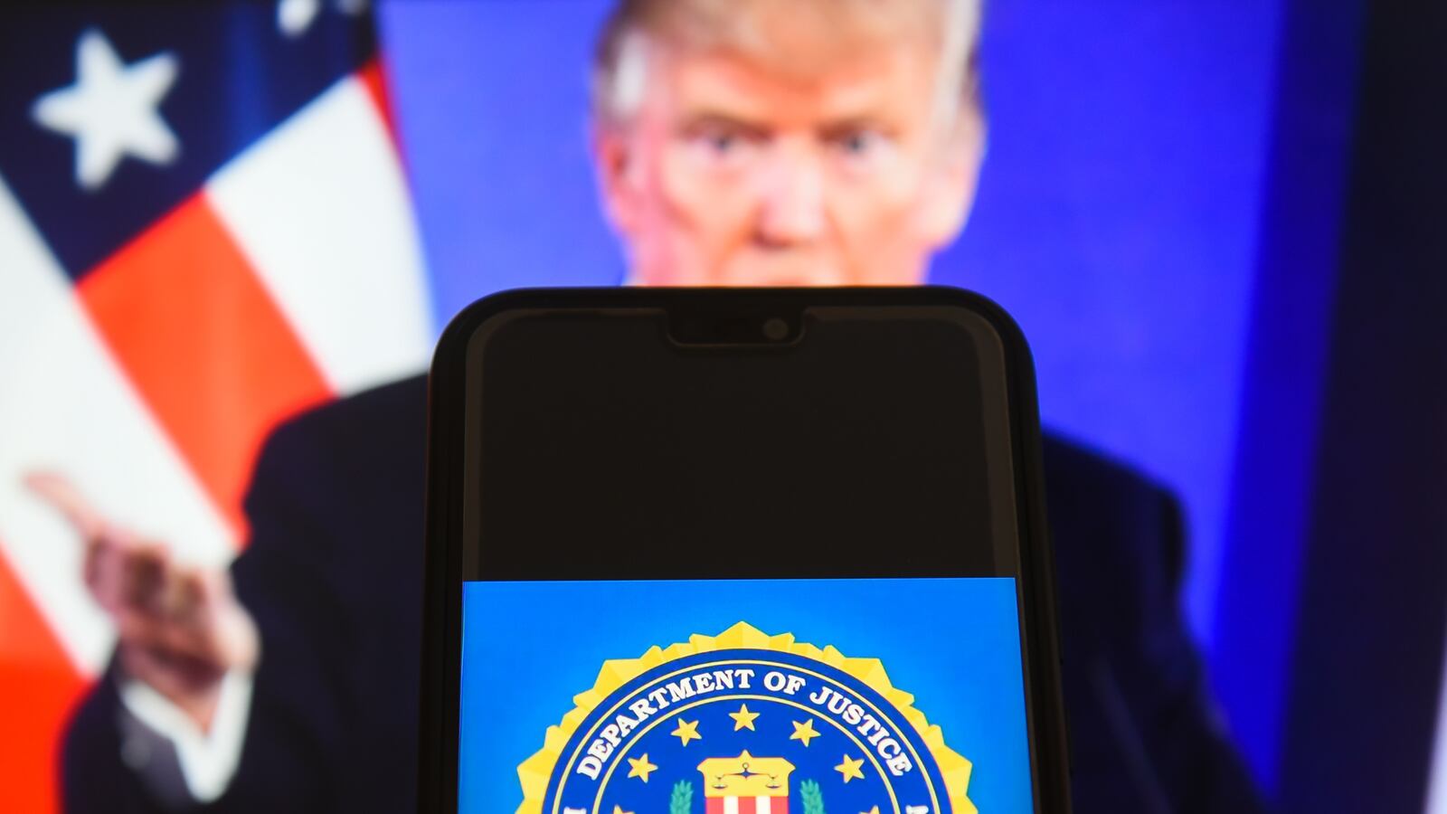 The Federal Bureau of Investigation (FBI) logo is seen with the President of the United States of America, Donald Trump in the background.