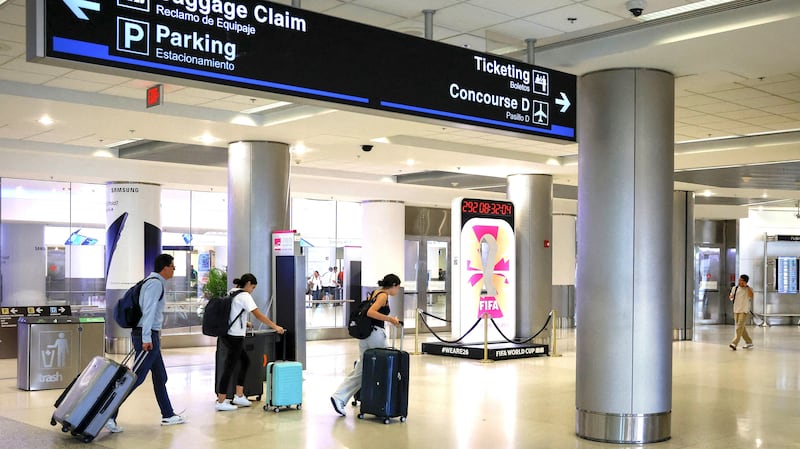 Travellers walk past an official FIFA World Cup countdown clock at Miami International Airport