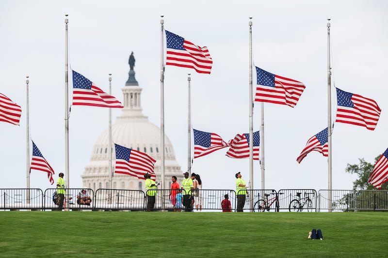 WASHINGTON, DC - AUGUST 25: American flags are lowered to half staff by National Park Service staff around the Washington Monument in honor of Dolly Parton's passing on August 25, 2026 in Washington, DC. U.S. President Donald Trump ordered the lowering of flags for one week after Parton died today at the age of 80. (Photo by Finn Gomez/Getty Images)