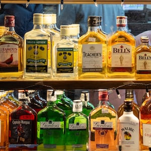 Liquor bottles lined up a store shelf.