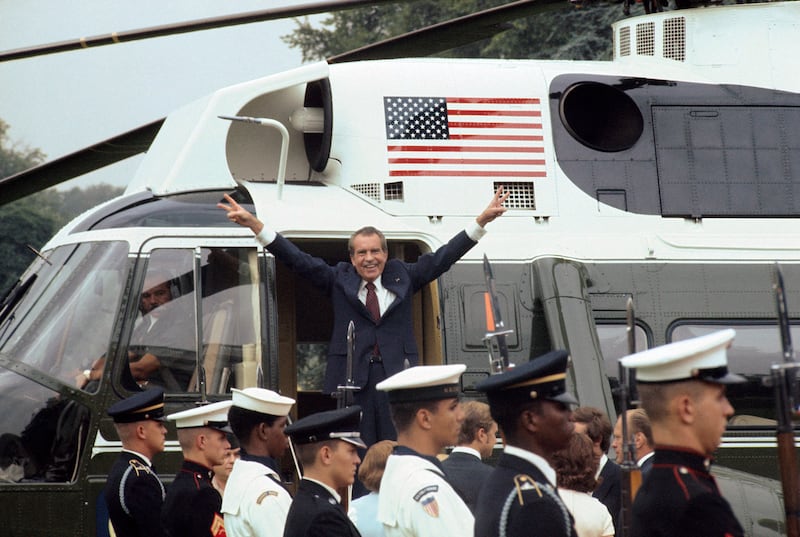 As he boards the White House helicopter after resigning the presidency, Richard M Nixon smiles and gives the victory sign.