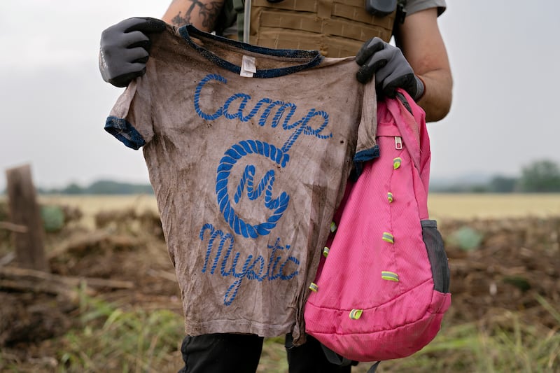 A search and rescue volunteer holds a T-shirt and backpack with the words Camp Mystic on them on July 6, 2025.