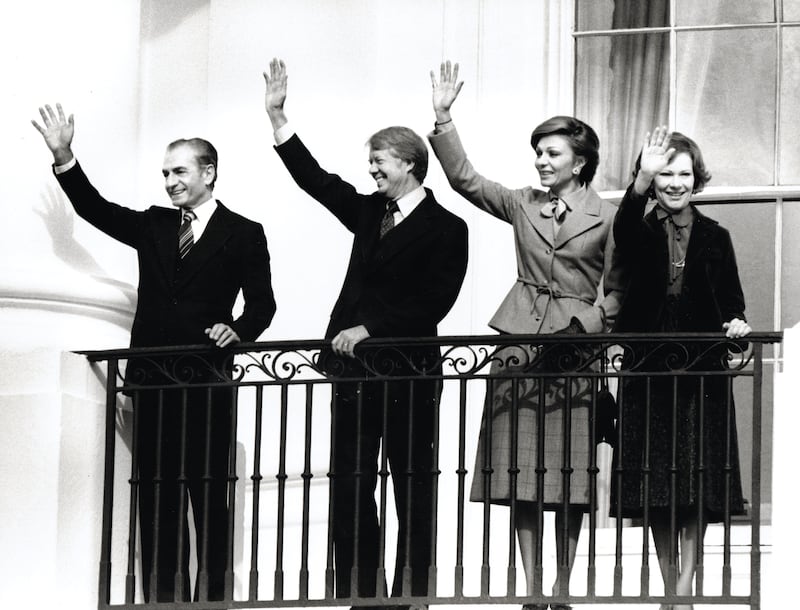 View of US President Jimmy Carter (second left) and First Lady Rosalynn Carter (right) hosting the Shah of Iran Mohammed Reza Pahlavi (right) and Shahbanu of Iran Farah Diba Pahlavi as they all wave from the Blue Room Balcony of the White House during a State Visit, Washington DC, November 15, 1977.
