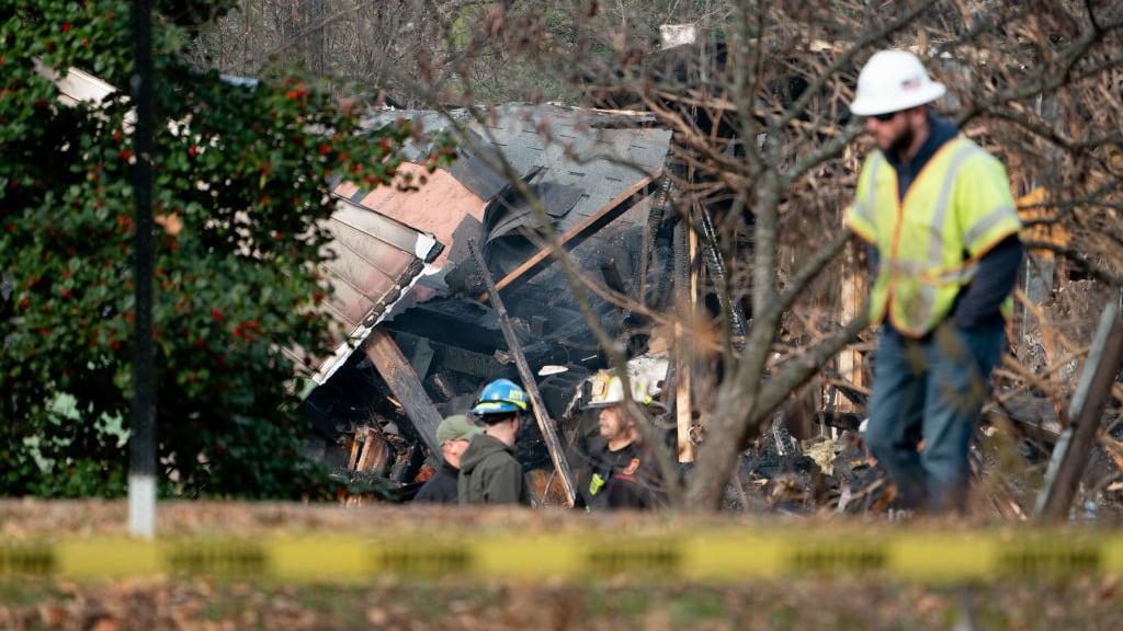 Workers walk near a home that exploded in Arlington, Virginia.