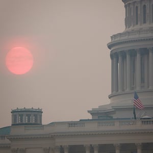 The sun rises behind the U.S. Capitol building during a summer heat wave as smoke from wildfires in Canada fills the air