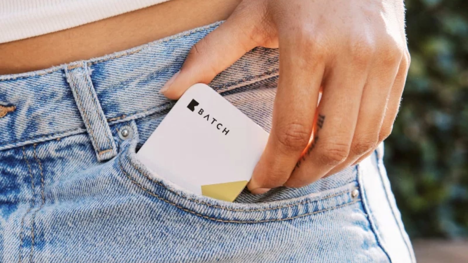 A person sliding a Batch Micro Mints tin into the front pocket of their jeans, showing the compact, pocket-sized design of the packaging.