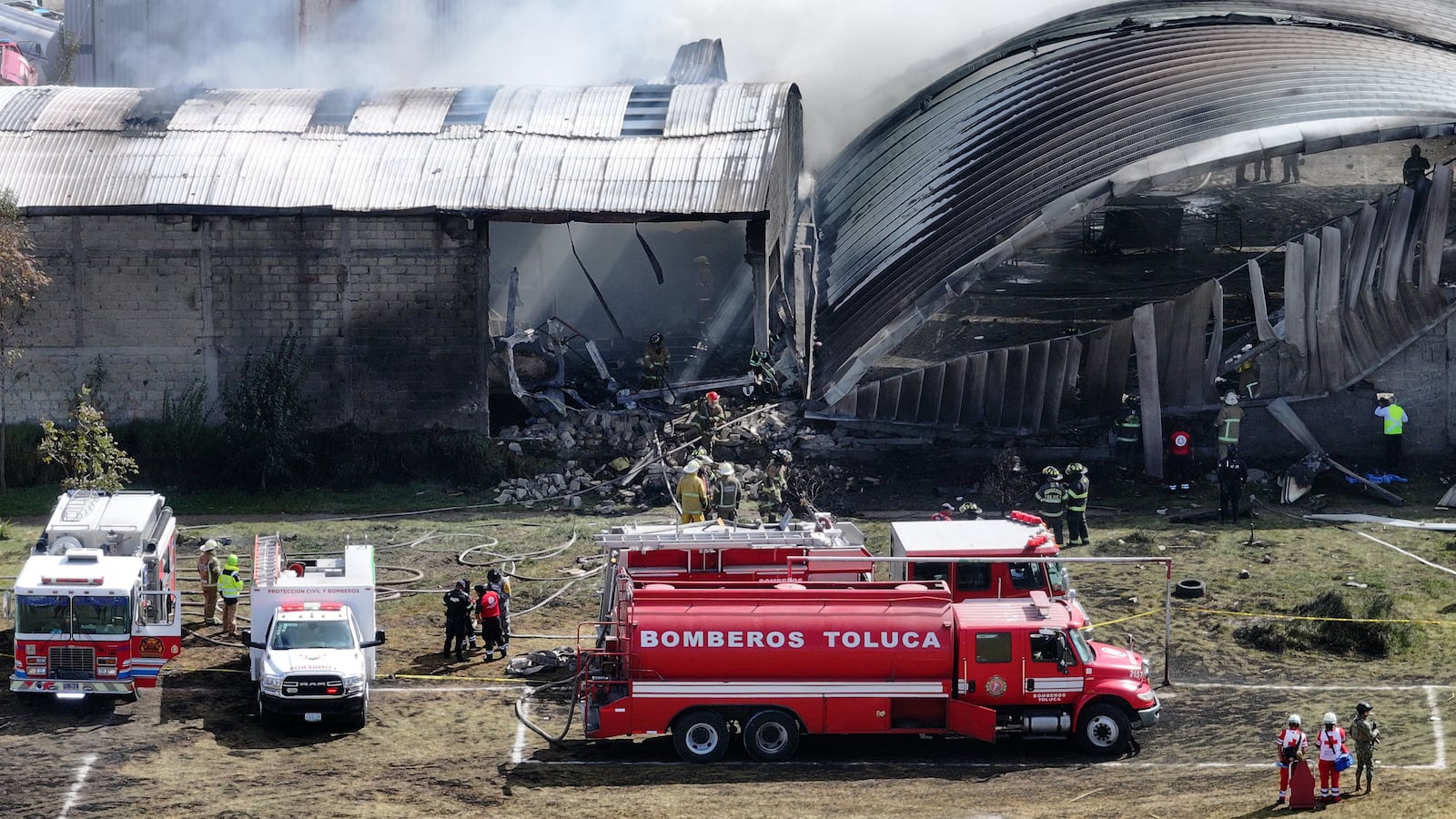 TOPSHOT - Aerial view of emergency services working to extinguish a fire caused by the crash of a Cessna Citation aircraft that struck an industrial warehouse in the Santa Maria Totoltepec neighborhood near Toluca International Airport in Mexico state on December 15, 2025. A small plane crashed shortly before reaching the airport in the central Mexican city of Toluca, killing at least four people, local Red Cross and authorities said.
