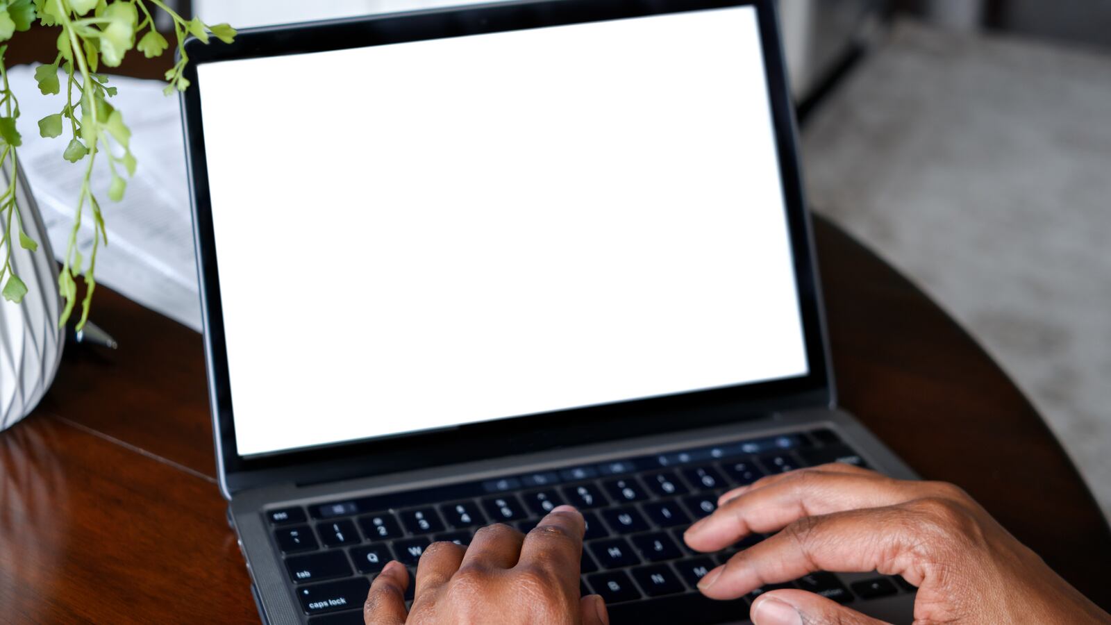 "Close-up of unrecognizable black woman working from home on laptop with blank white screen template for design mockup"