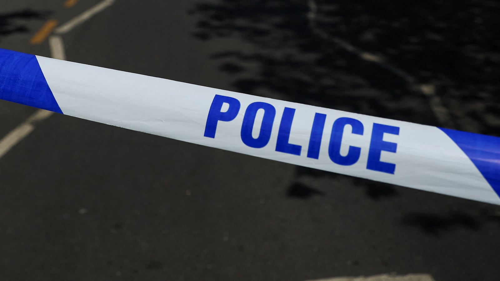 Blue and white police tape is put across a street in England.