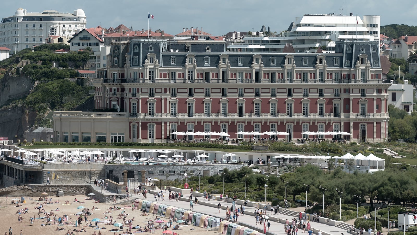 People swim in the sea and walk on the beach in front of the \"Hotel du Palais\" in Biarritz.