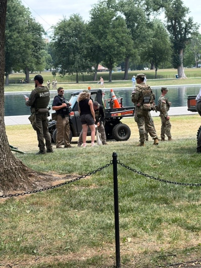 An officer searches the bag of a woman surrounded by law enforcement officers near the Lincoln Memorial Reflecting Pool on June 22, 2026.