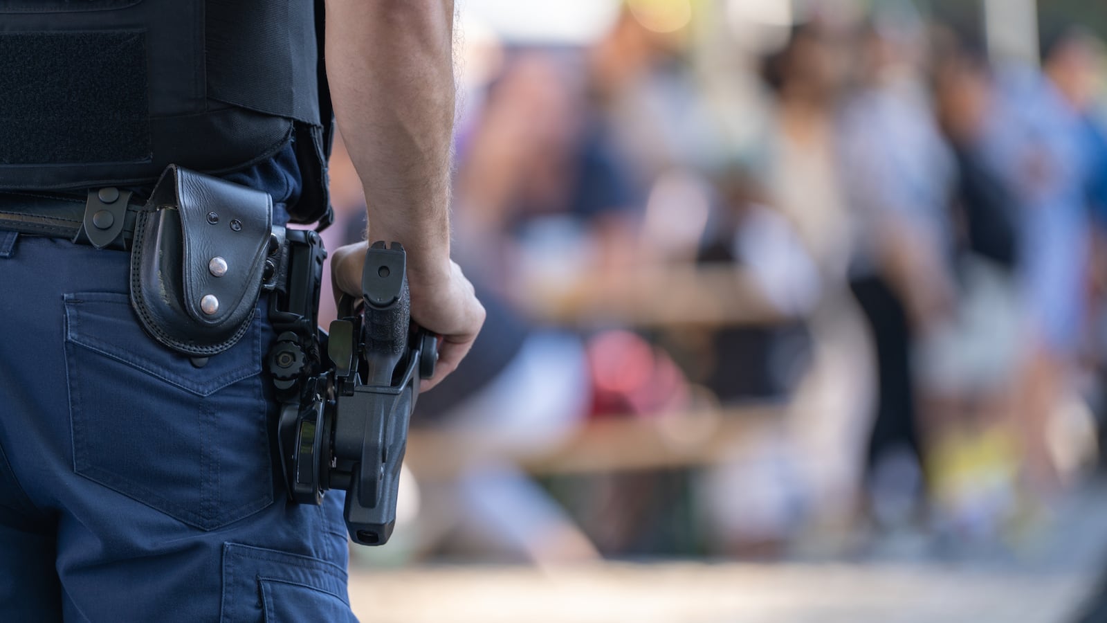 A police officer monitors a parade, with his gun in frame.