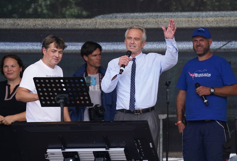 BERLIN, GERMANY - AUGUST 29: Robert F. Kennedy Jr. (C), nephew of former U.S. President John F. Kennedy, greets people from a wide spectrum, including coronavirus skeptics, conspiracy enthusiasts, right-wing extremists, religious conservatives, hippies and others gathered under the Victory Column in the city center to hear speeches during a protest against coronavirus-related restrictions and government policy as Michael Ballweg (L), founder of the Querdenker movement, looks on on August 29, 2020 in Berlin, Germany. City authorities had banned the planned protest, citing the flouting of social distancing by participants in a similar march that drew at least 17,000 people a few weeks ago, but a court overturned the ban. (Photo by Sean Gallup/Getty Images)