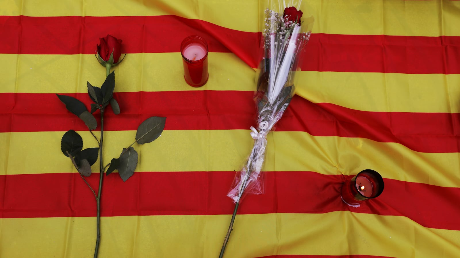 Roses and candles placed on Catalan flag at impromptu memorial service for Barcelona attack victims.