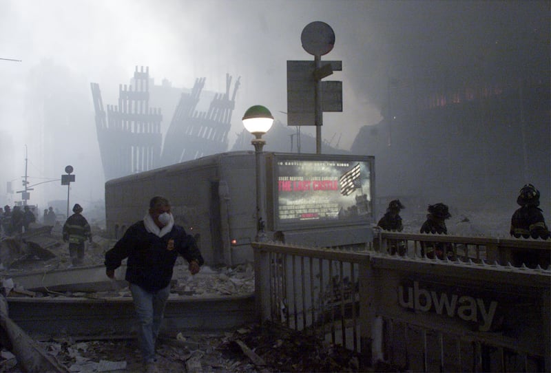 The wreck of the World Trade Center smoulders in the background as a man
passes a subway stop after two planes crashed into each of the twin towers
in New York on September 11, 2001. Three hijacked planes crashed into major
U.S. landmarks on Tuesday, destroying both of New York's mighty twin towers
and plunging the Pentagon in Washington into flames, in an unprecedented
assault on key symbols of U.S. military and financial power.