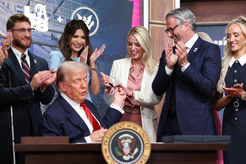 DHS Secretary Kristi Noem stands behind President Donald Trump as he hands off a pen used to sign his executive order just moments after flubbed her name and instead mentioning pro-golfer Cristie Kerr before correcting himself.