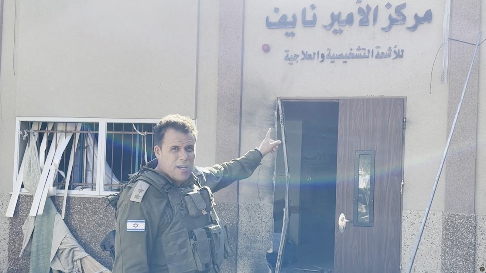 An Israeli soldier in uniform points to signage outside Al Shifa hospital complex.