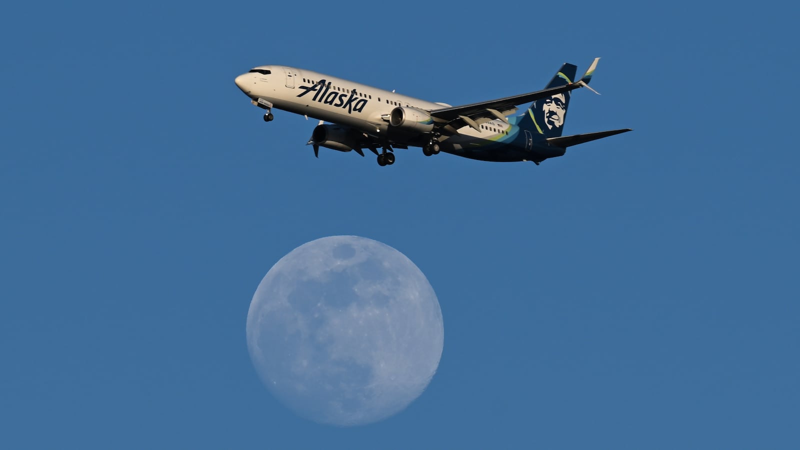 An Alaska Airlines Boeing 737 plan is flying above the 96% of Waxing Gibbous moon in San Mateo, California, United States on February 10, 2025.