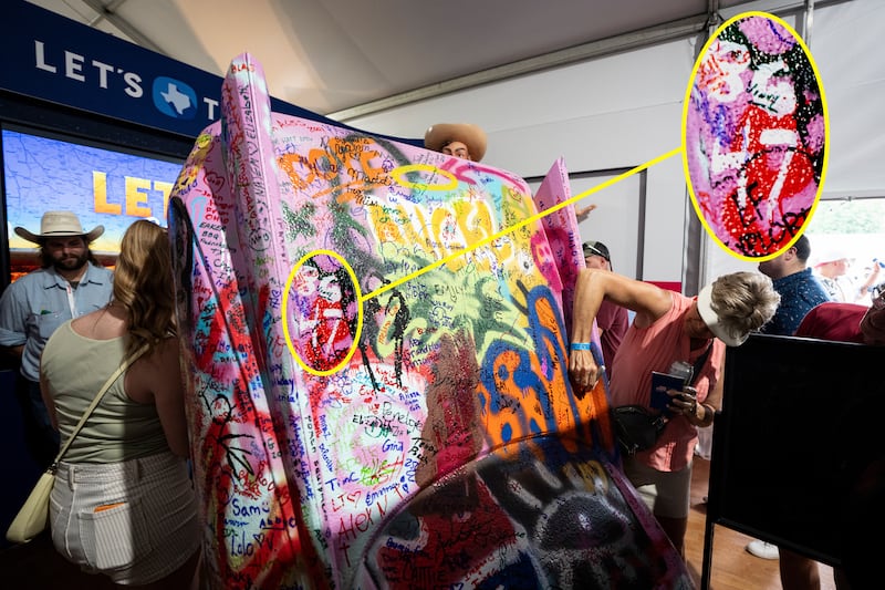 A visitor signs a replica of the Cadillac Ranch at the Texas exhibit on the third day of the "Great American State Fair" on the National Mall as seen from the Washington Monument on June 27, 2026 in Washington, DC.