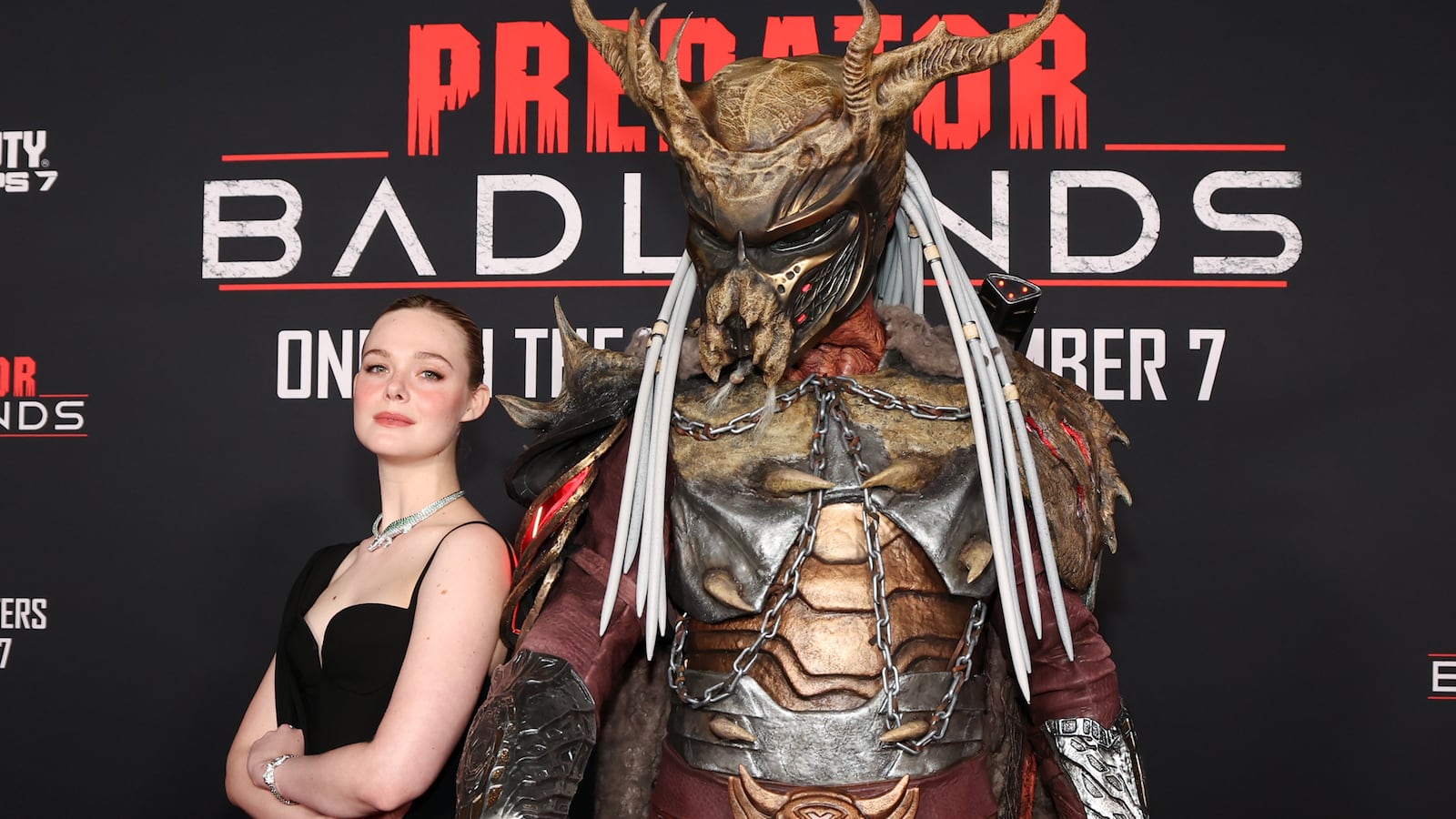 LOS ANGELES, CALIFORNIA - NOVEMBER 03: (L-R) Elle Fanning poses with 'Father' at the premiere of Predator: Badlands at TCL Chinese Theater on November 03, 2025 in Los Angeles, California. (Photo by Jesse Grant/Getty Images for 20th Century Studios)