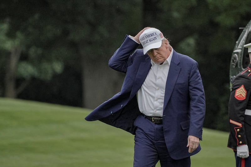 U.S. President Donald Trump holds his hat as he walks on the South Lawn of the White House in Washington, D.C., U.S., May 25, 2025.