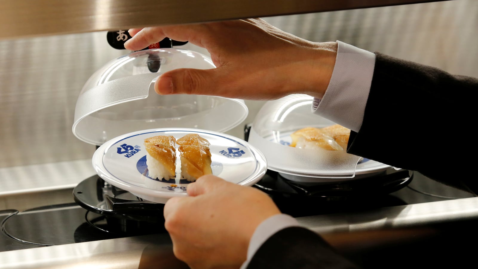 A man picks up a sushi from conveyor belt during a media event in Tokyo, Japan, Jan. 21, 2020.