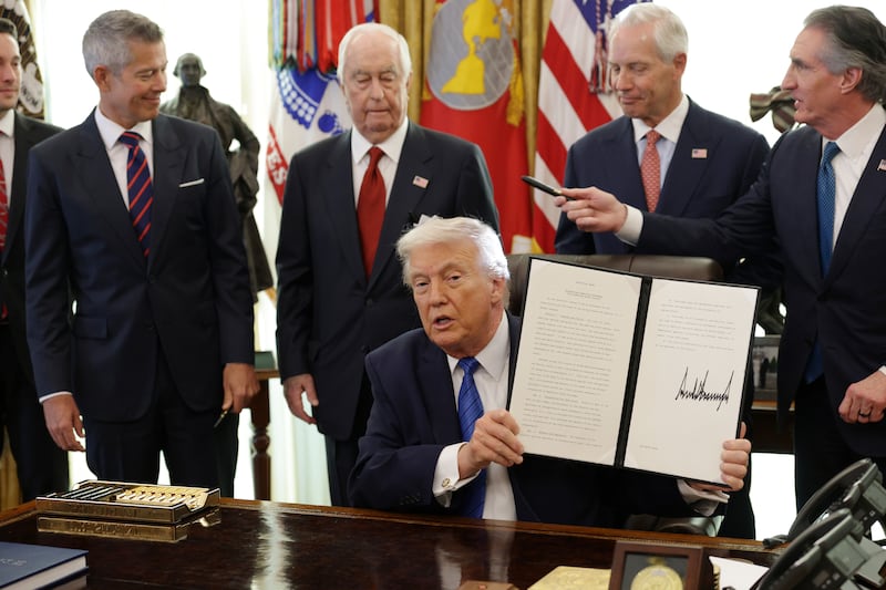 President Donald Trump holds up a signed executive order alongside Secretary of Transportation Sean Duffy, Roger Penske, Chair of the Penske Corporation, Bud Denker, President of Penske Corporation, and U.S. Interior Secretary Doug Burgum, in the Oval Office of the White House on January 30, 2026 in Washington, DC.