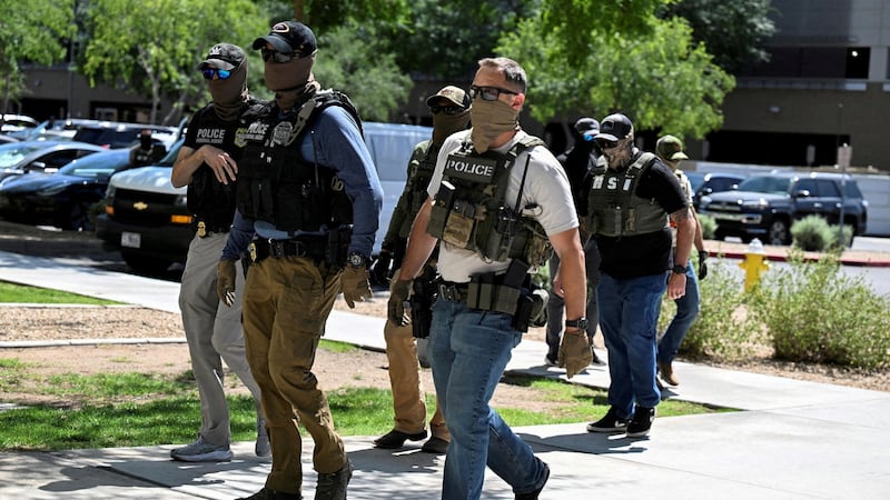 FILE PHOTO: Masked law enforcement officers, including HSI and ICE agents, walk into an immigration court in Phoenix, Arizona, U.S., May 21, 2025.  REUTERS/Caitlin O'Hara/File Photo