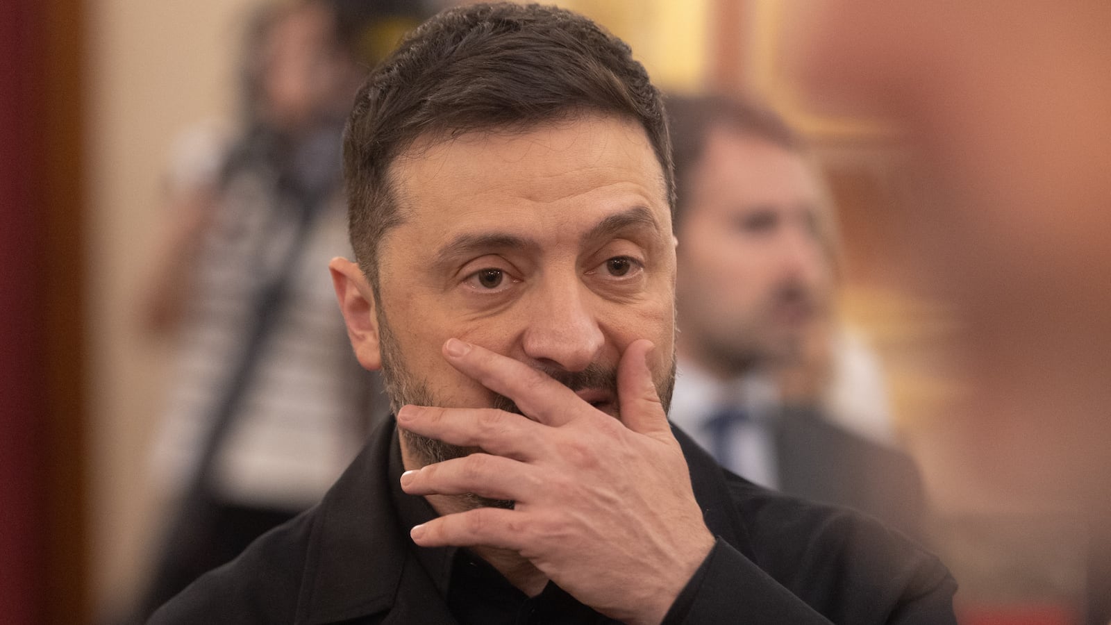 Ukraine's president Volydymr with his hand partially covering his lower face