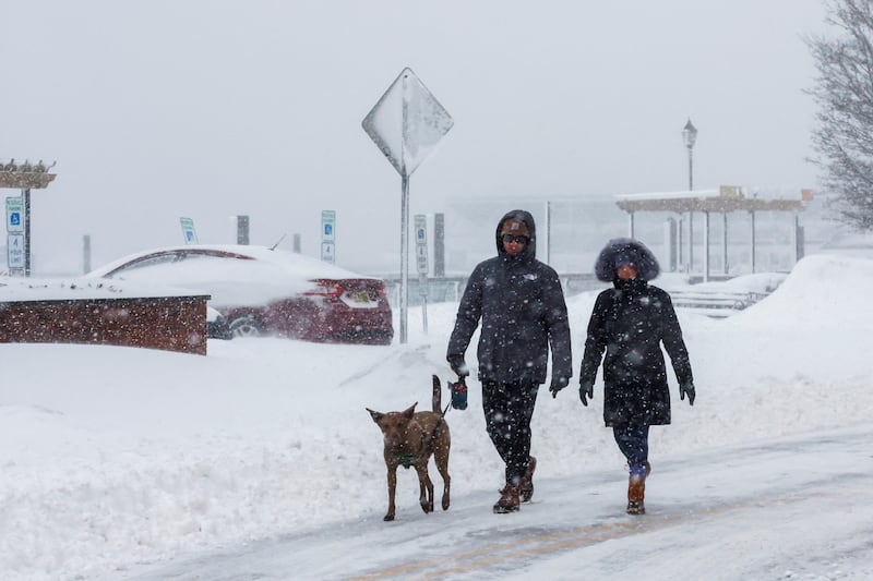 People walk a dog in local street covered with snow during a winter storm in Hoboken, New Jersey, U.S., February 23, 2026.