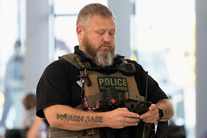 An Immigration and Customs Enforcement (ICE) agent looks at their phone.