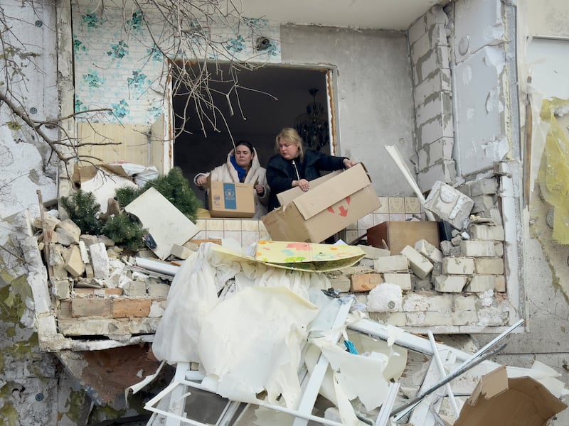 Residents of a destroyed apartment in Zolochiv throw debris out of their window in Zolochiv on February 25, 2025.