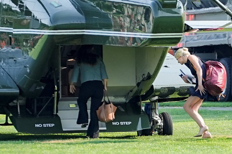 Donald Trump's executive assistant, Natalie Harp, carries a duffel bag as the president leaves for a weekend trip on Aug. 14.