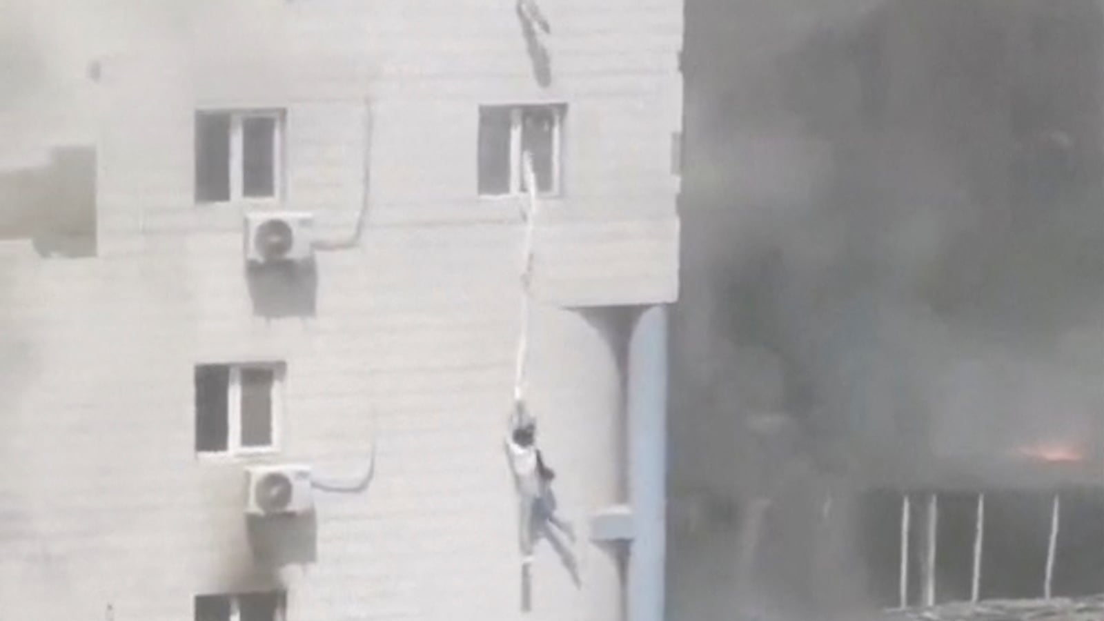 People try to escape from windows following a fire at the Changfeng Hospital, in Beijing, China, April 18, 2023, in this screen grab obtained from a social media video.