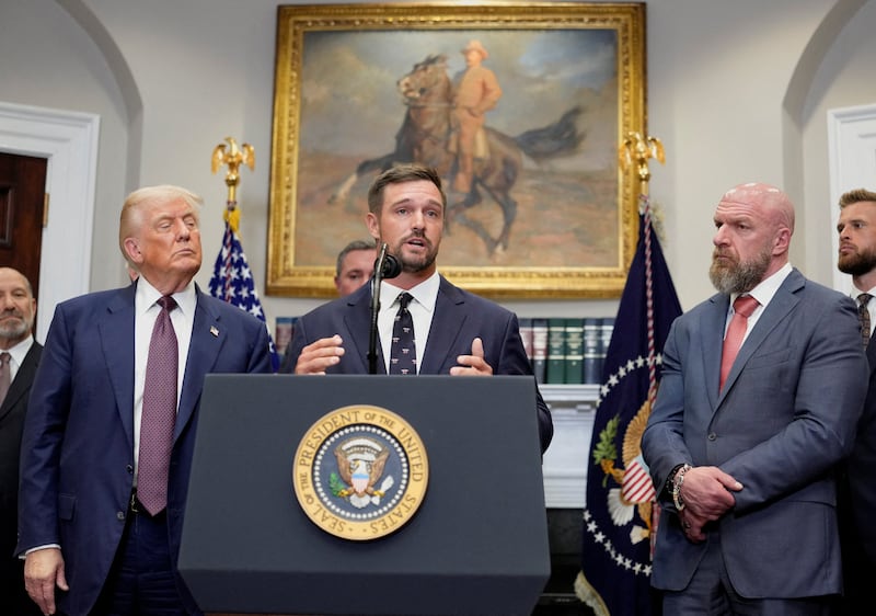 Golfer Bryson DeChambeau, next to U.S. President Donald Trump and WWE Chief Content Officer and businessman Paul Michael Levesque, also known professionally as Triple H, delivers remarks in the Roosevelt Room at the White House in Washington, D.C., U.S., July 31, 2025.