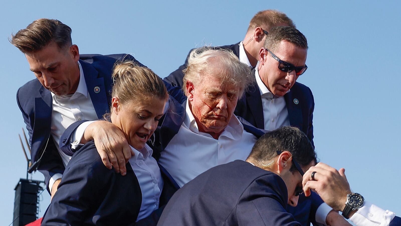 BUTLER, PENNSYLVANIA - JULY 13: Republican presidential candidate former President Donald Trump is rushed offstage by U.S. Secret Service agents after being grazed by a bullet during a rally on July 13, 2024 in Butler, Pennsylvania. Butler County district attorney Richard Goldinger said the shooter is dead after injuring former U.S. President Donald Trump, killing one audience member and injuring another in the shooting. (Photo by Anna Moneymaker/Getty Images)